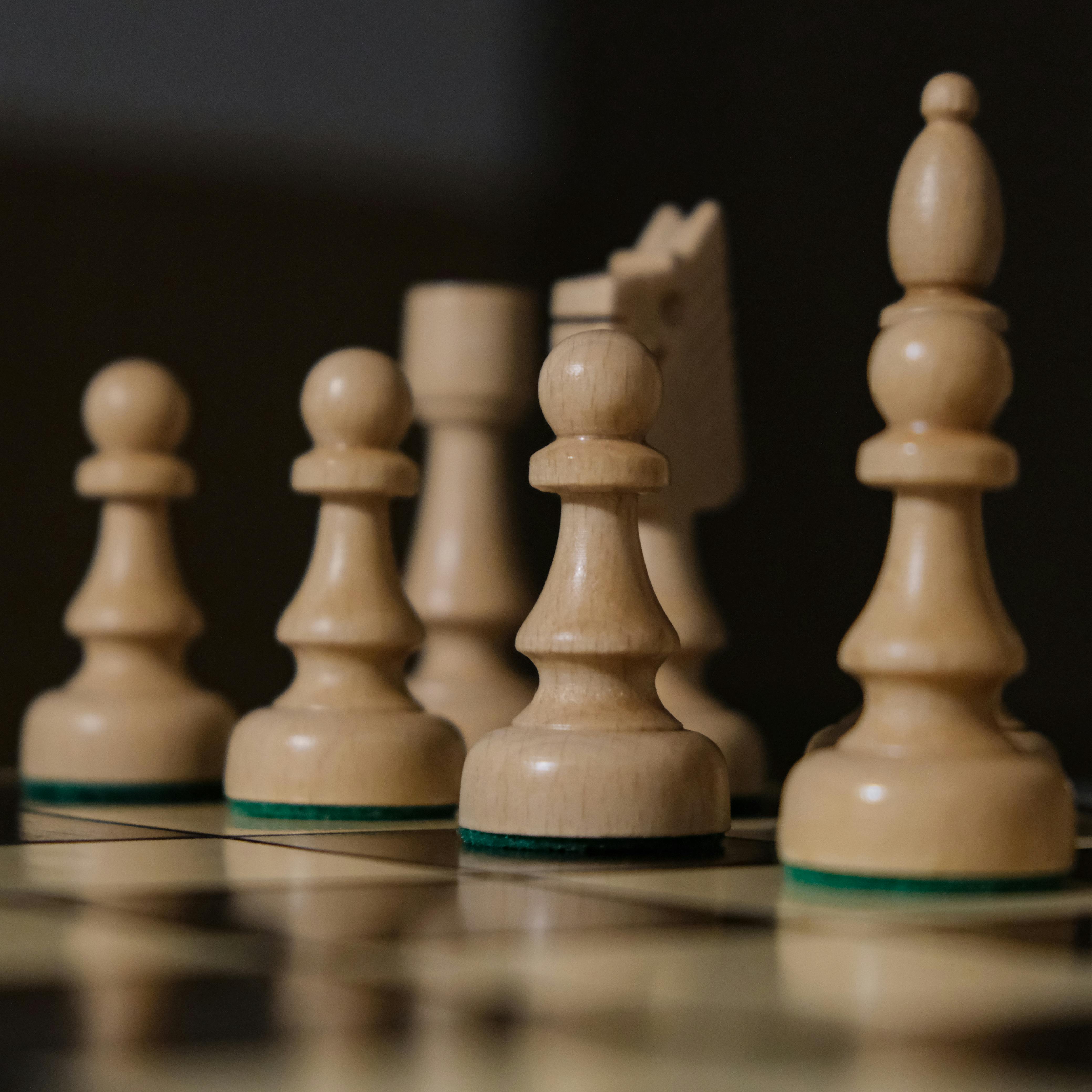 Detailed view of chess pieces lined up on a wooden board, focusing on pawns.